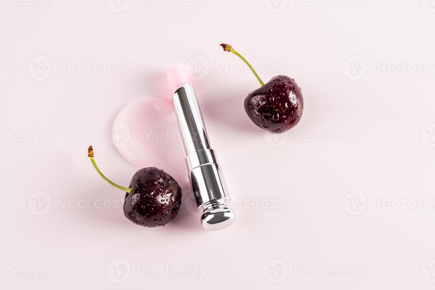 A beautiful silver package of lip balm or lipstick lies on sample of the texture of the product among ripe cherries. top view. A copy space. layout. photo