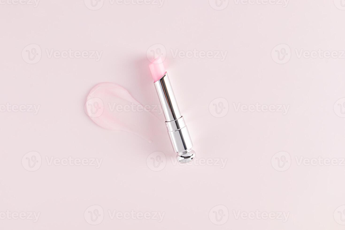 Open silver packaging of fruit flavored balm or lipstick on a pink background with a sample of the texture of the balm stroke. top view. Presentation. photo