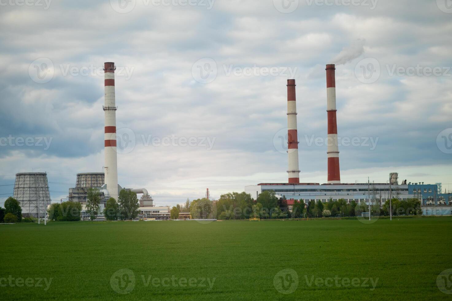 A large factory with two chimneys and smoke stacks photo
