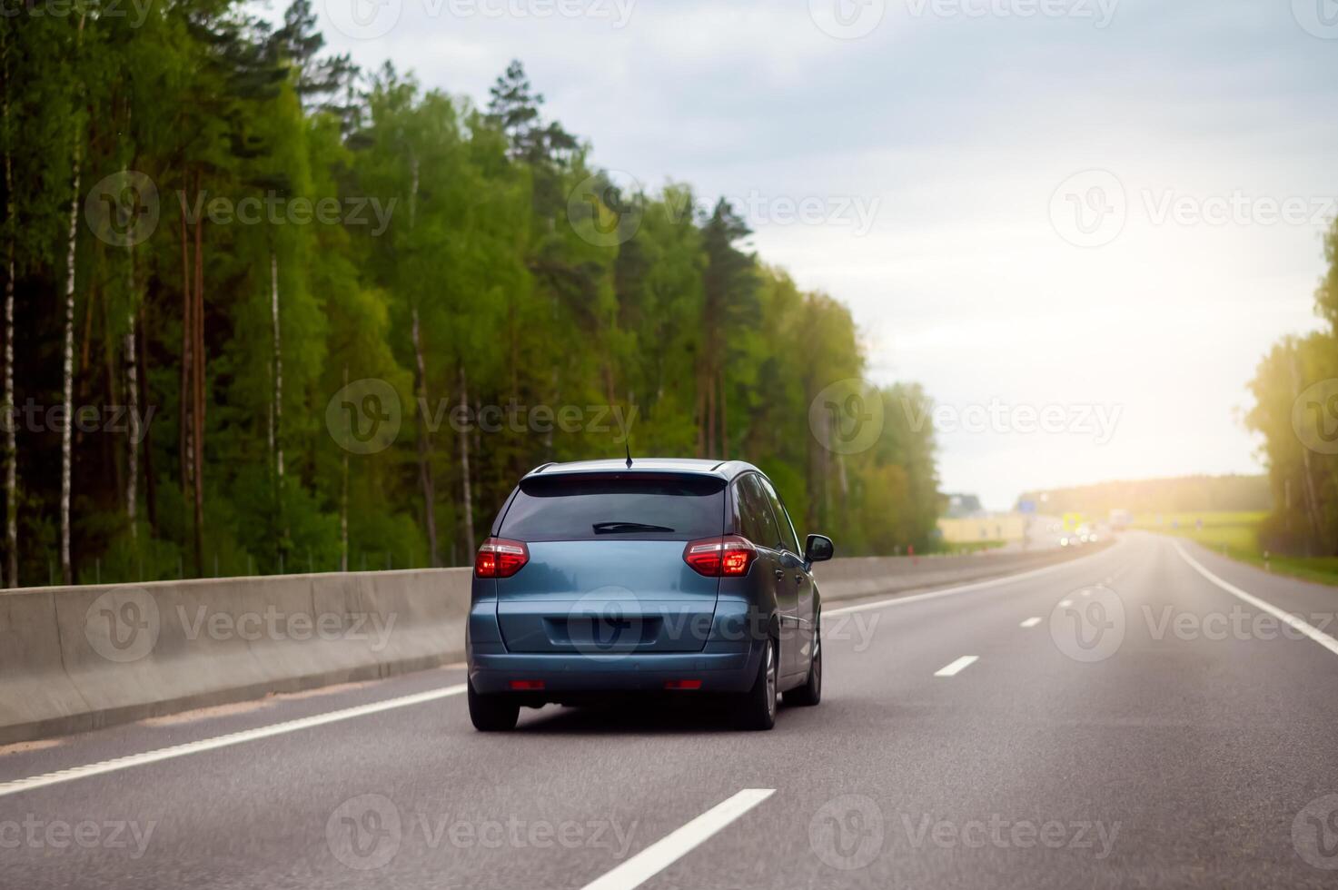A car driving down the road in the woods photo