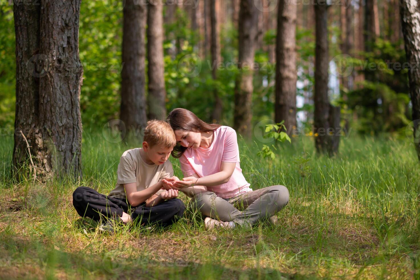 mother and son are sitting side by side in a forest photo