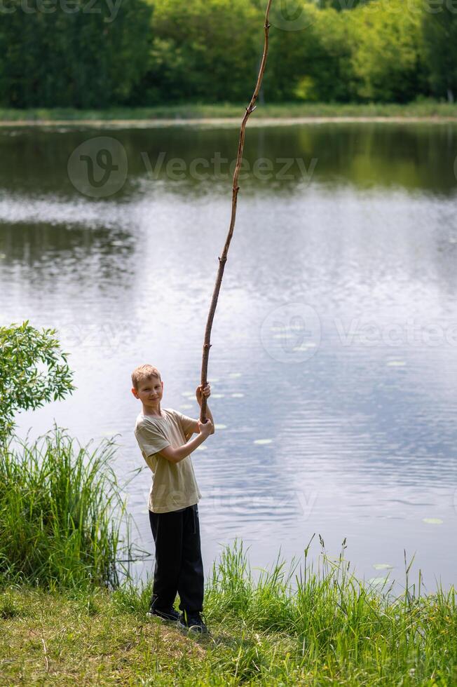 A boy holding a long stick in the grass photo