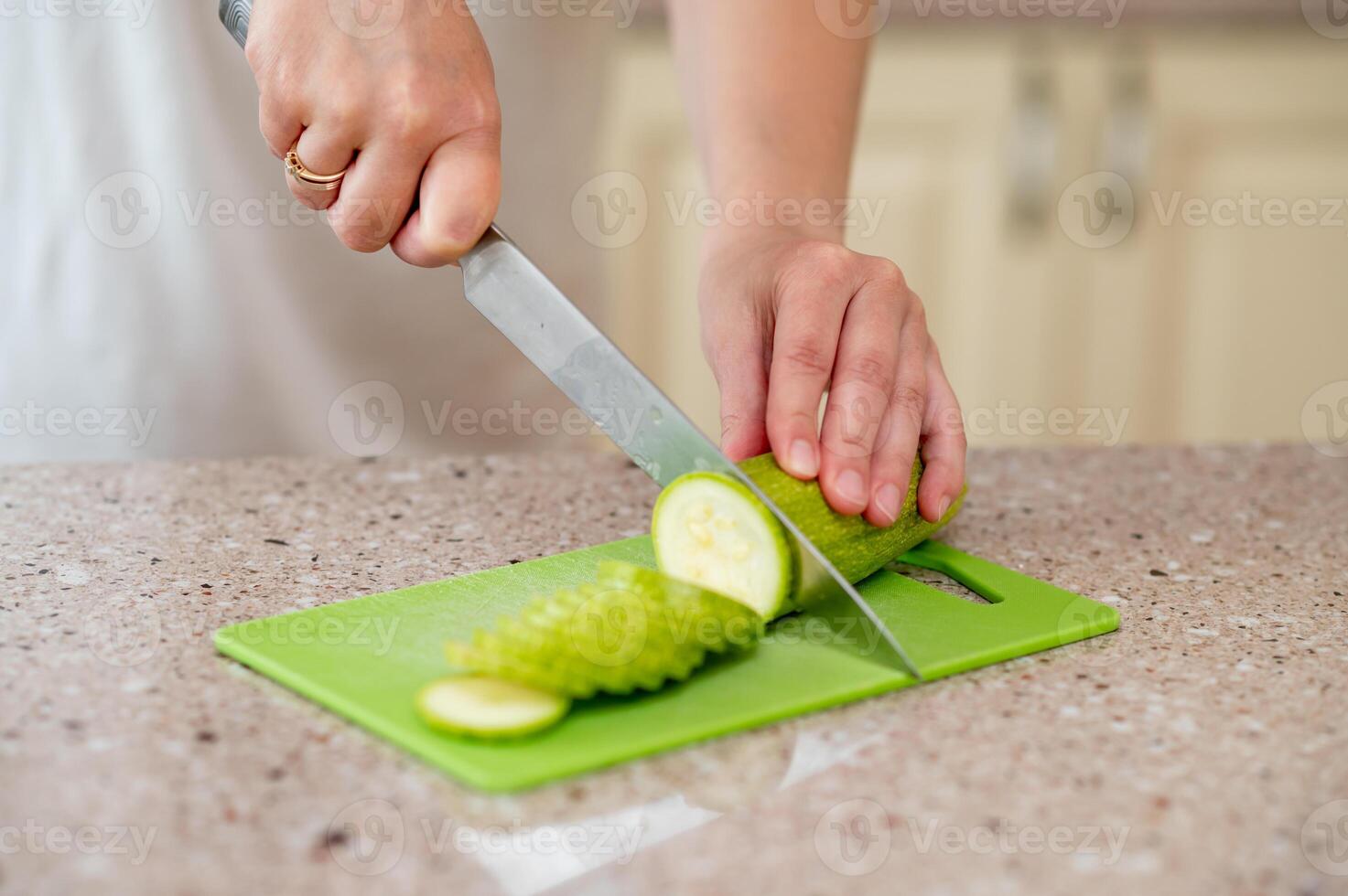 A person cutting a cucumber on a green cutting board photo