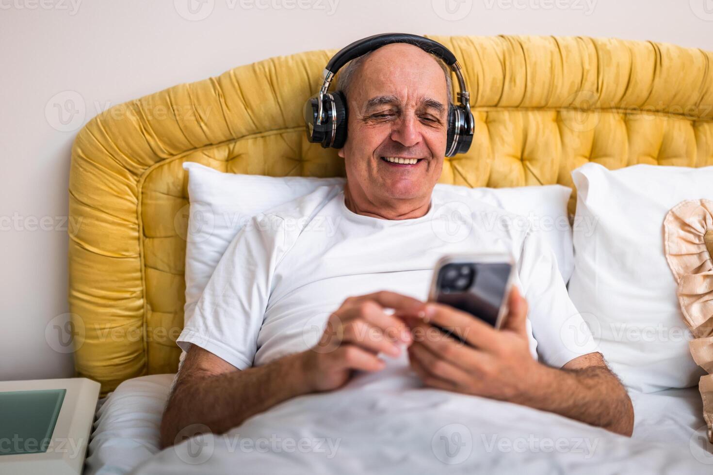 Mature man smiling as he talks on his smartphone with wireless headphones, reflecting happiness and connectivity in retirement years. photo