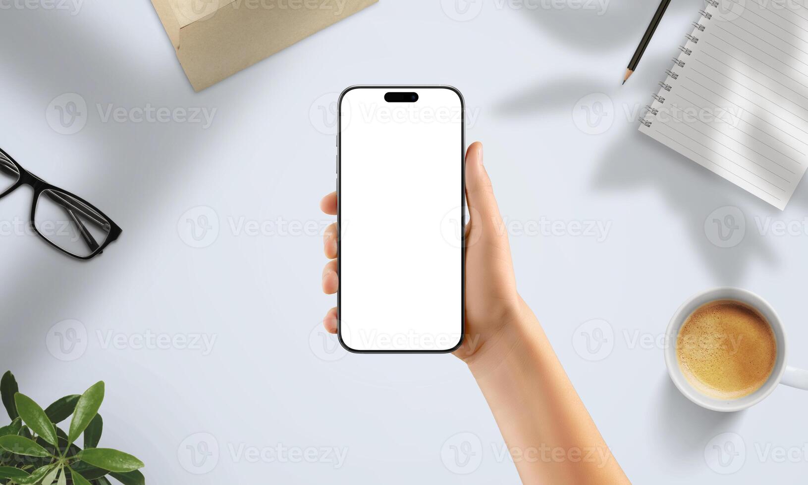 Hand holding smartphone with blank screen in creative workspace. Surrounded by coffee, notebook, glasses, and soft natural shadows photo