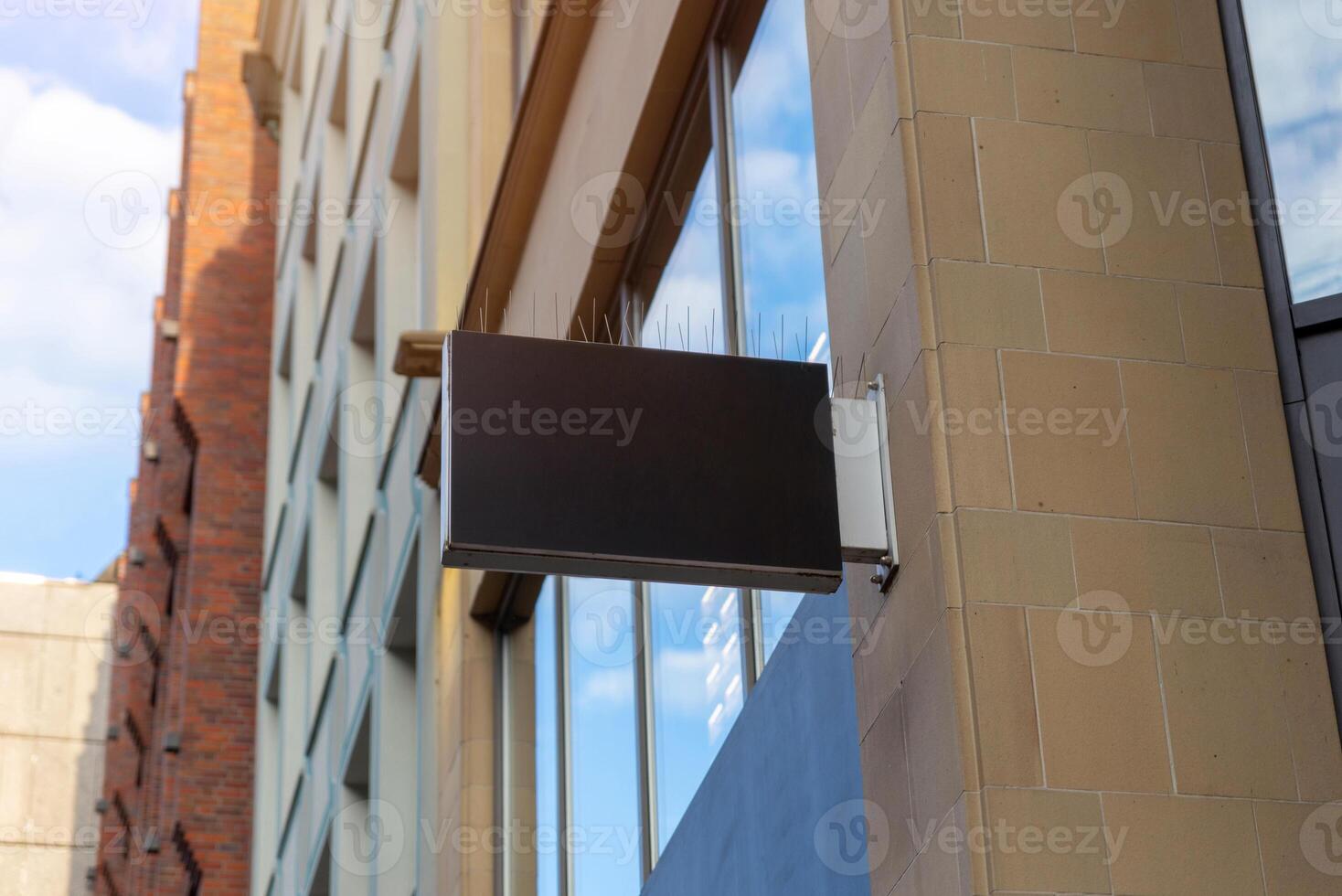 Black rectangular store sign with bird spikes on top, ideal for urban branding mockups, commercial signage or corporate advertising visuals photo