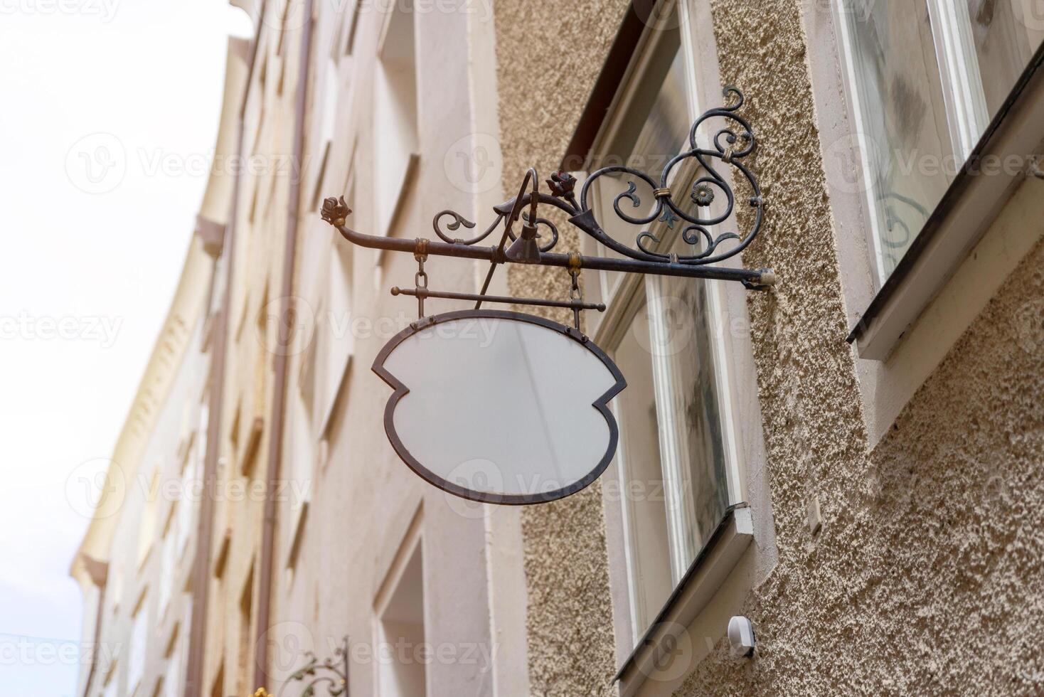 Unique vintage blank signage with wrought iron bracket, perfect for old town shops, cafes, or custom logo mockups in rustic settings. photo