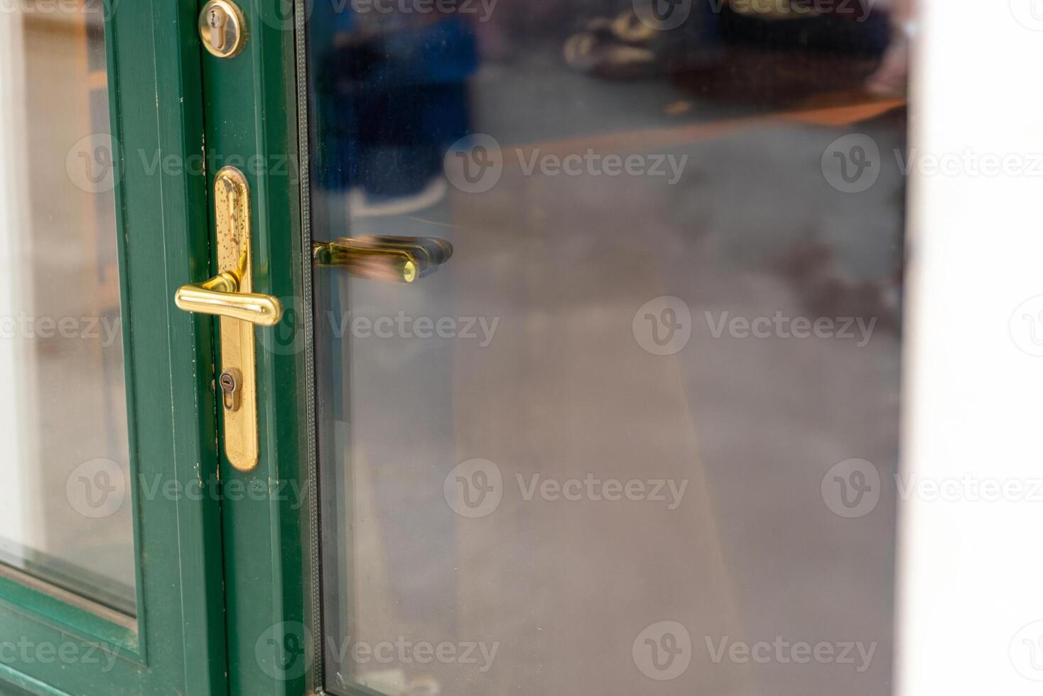 Golden door handle on green frame with glass reflection, ideal for design elements, access visuals, and architectural or security themed content. photo