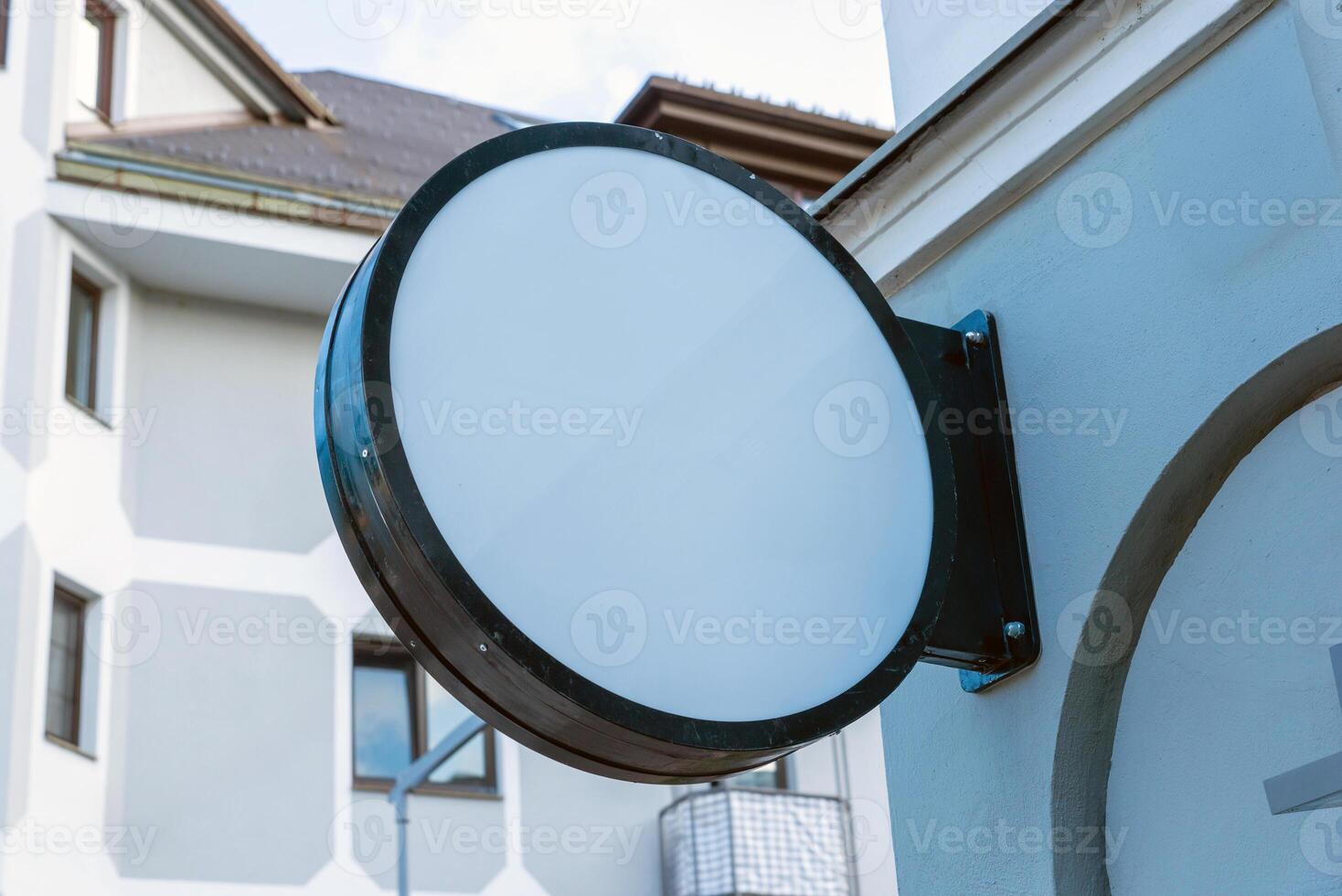 Blank circular signage on exterior wall, ready for custom logo, storefront branding or commercial display presentation in daylight environment photo