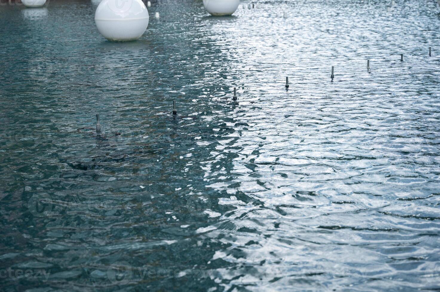 close-up of water surface, with small ripples of water from wind. city fountain, water surface with round balls. On the surface of the fountain there are glass matte white balls of different sizes photo
