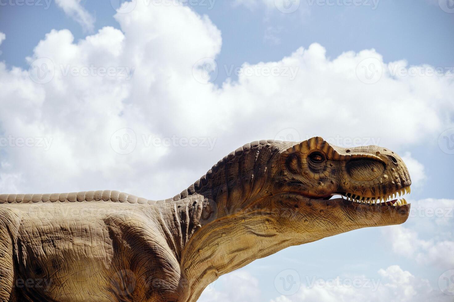 A huge tyrannosaurus dinosaur, a close-up of the dinosaur's head against the sky and clouds. With space for copying. The dinosaur in profile, you can see its teeth and huge mouth photo