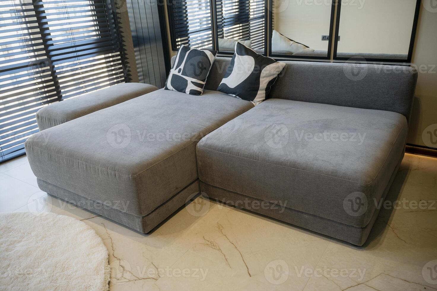 Ergonomic gray, velour sofa standing near a large window with wooden blinds with copy space photo