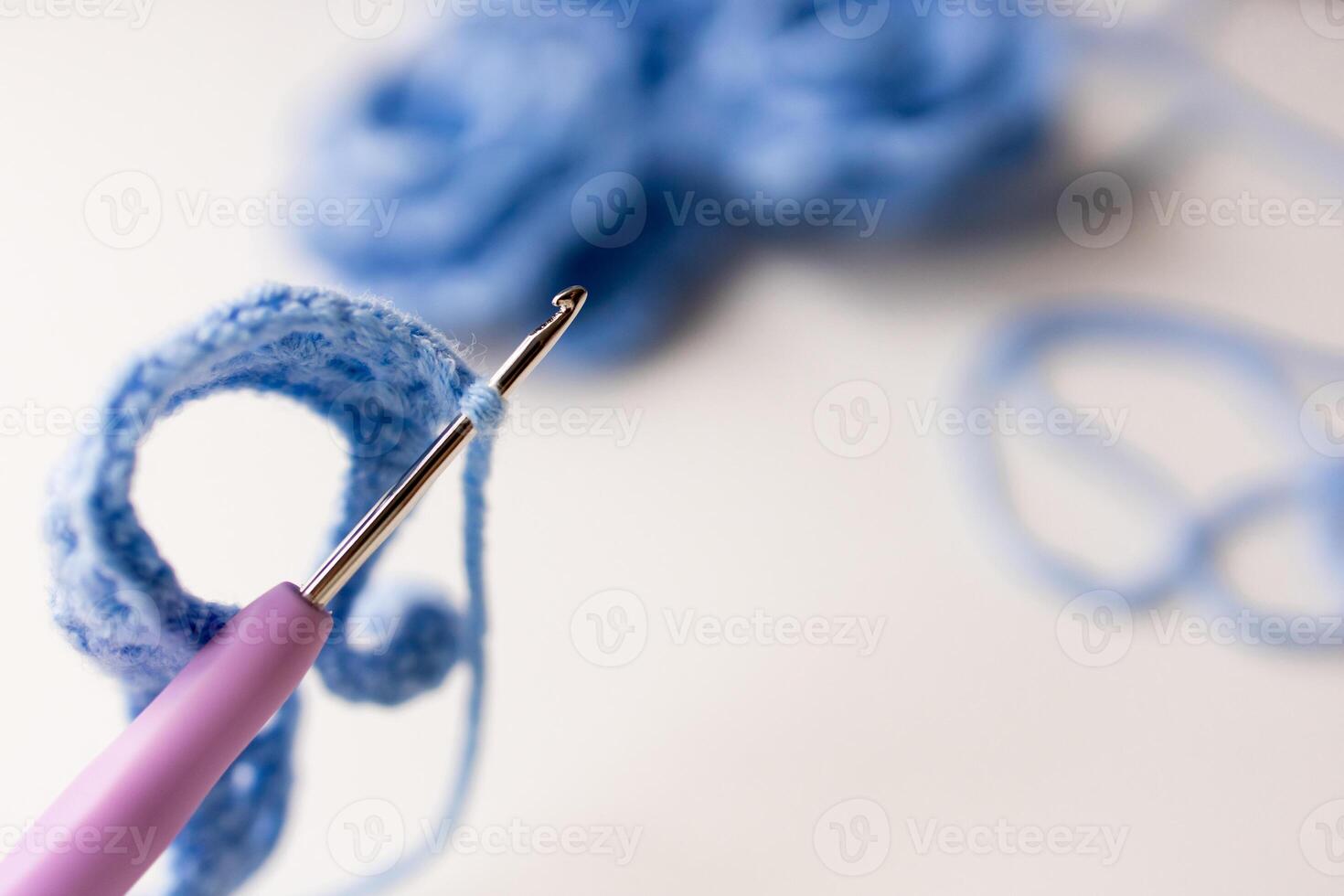 Close up of crochet hook with blue yarn loop in focus photo