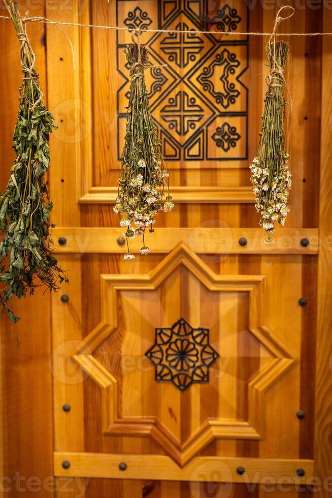 Dried Herbs Hanging Against Ornate Wooden Background photo