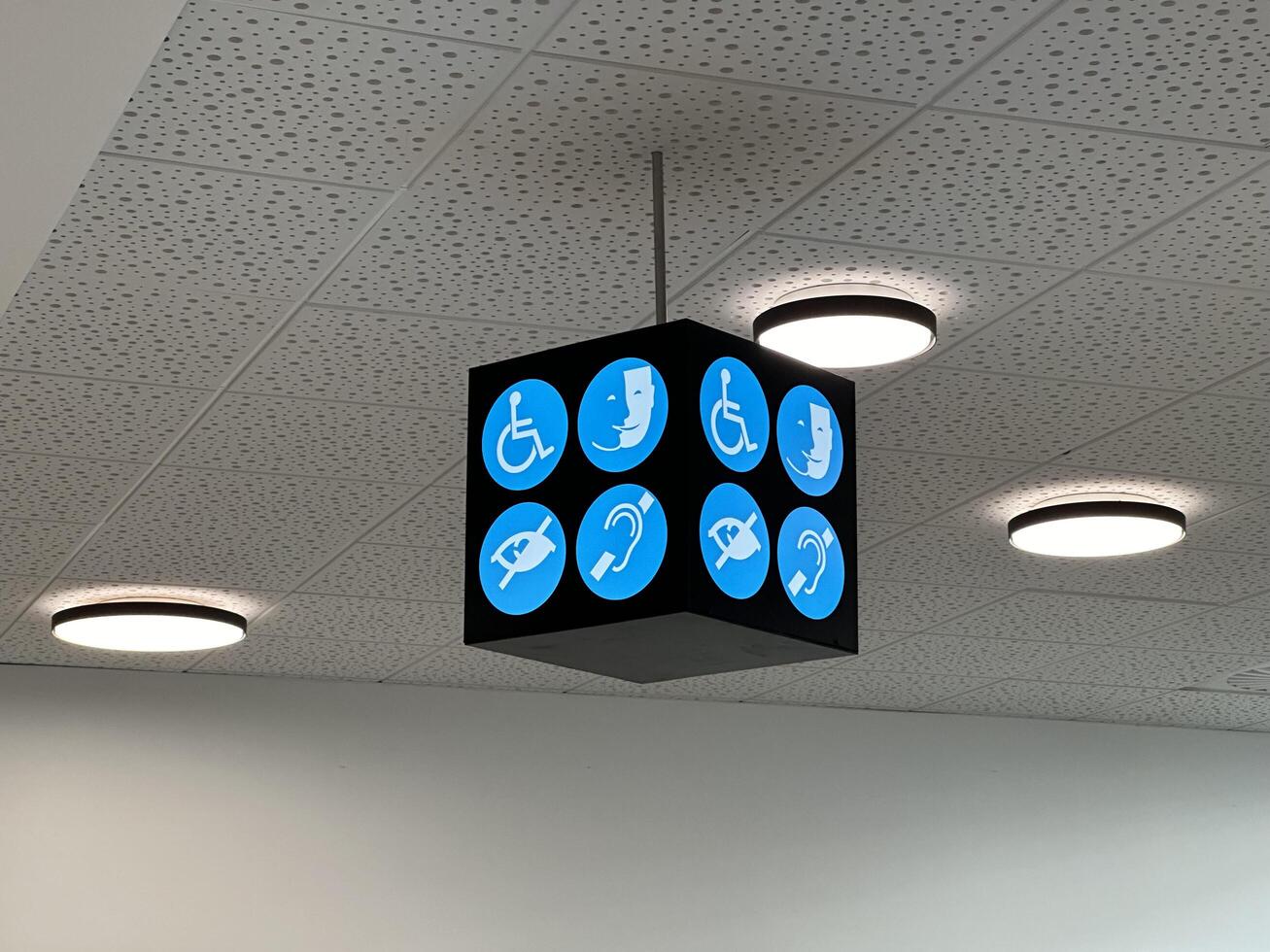 Nice, France - May 10, 2025 Accessibility sign hanging from ceiling, featuring various symbols for disabled services, illuminated by modern ceiling lights in a public building environment photo