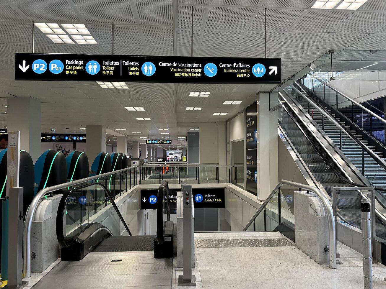 Nice, France - May 10, 2025 Modern airport interior showcasing directional signage and escalators, guiding travelers to parking, restrooms, and vaccination center in a spacious environment photo