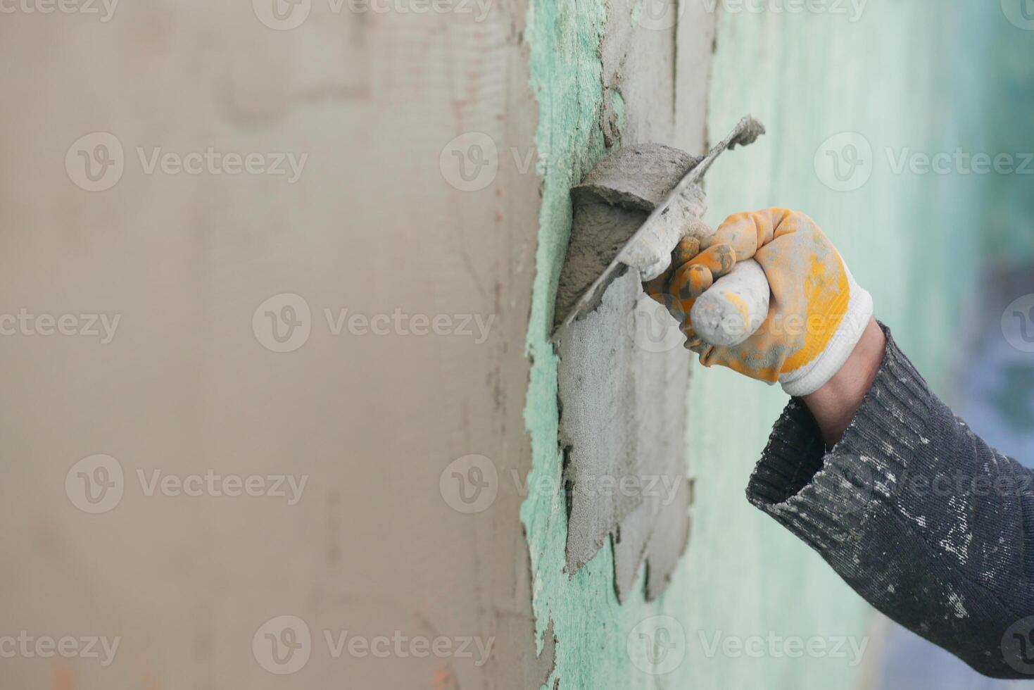 Worker applying plaster to wall in construction site photo