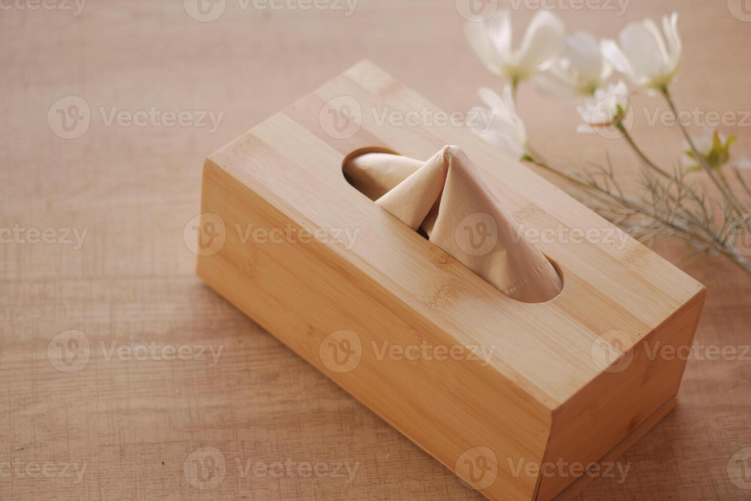 Elegant wooden tissue box with flowers on table photo