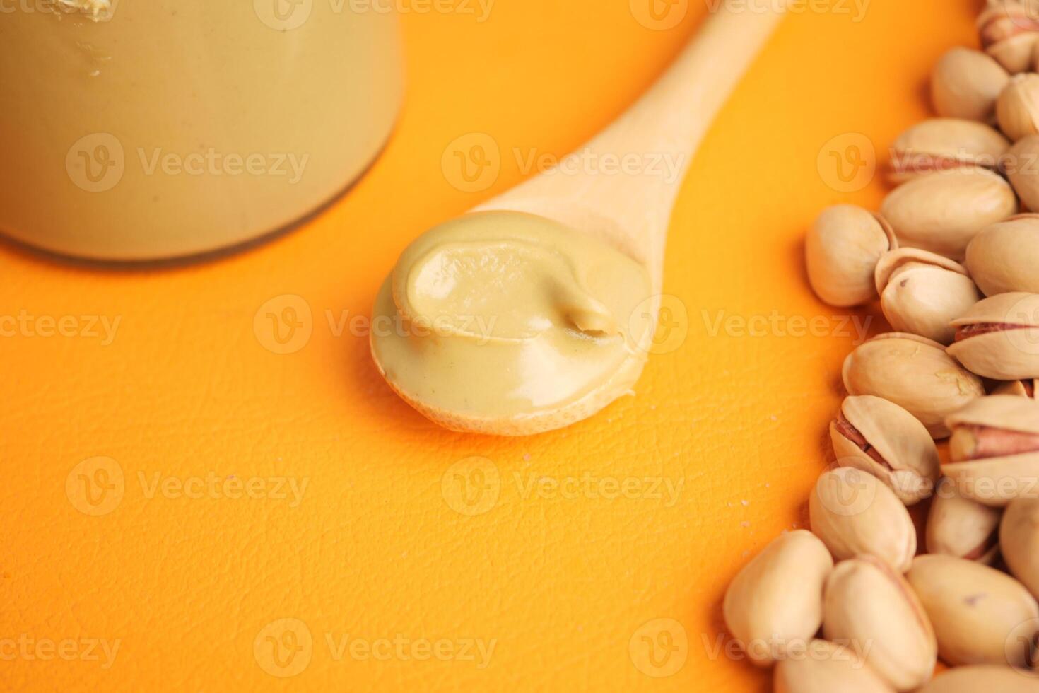 Pistachio butter spread on a spoon with nuts nearby photo