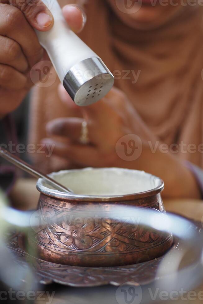 Adding seasoning to a traditional dish in a cozy setting photo