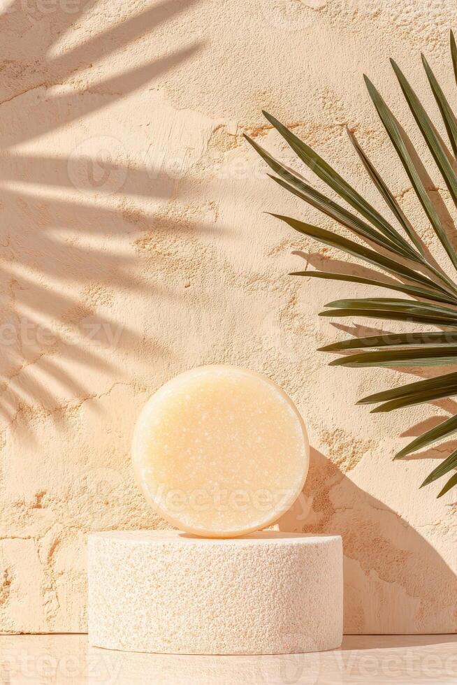 Solid Soap Bar rests atop Cylinder Stand. Palm Leaf casts Shadow on Textured Surface. Concept displaying Zero Waste Living photo