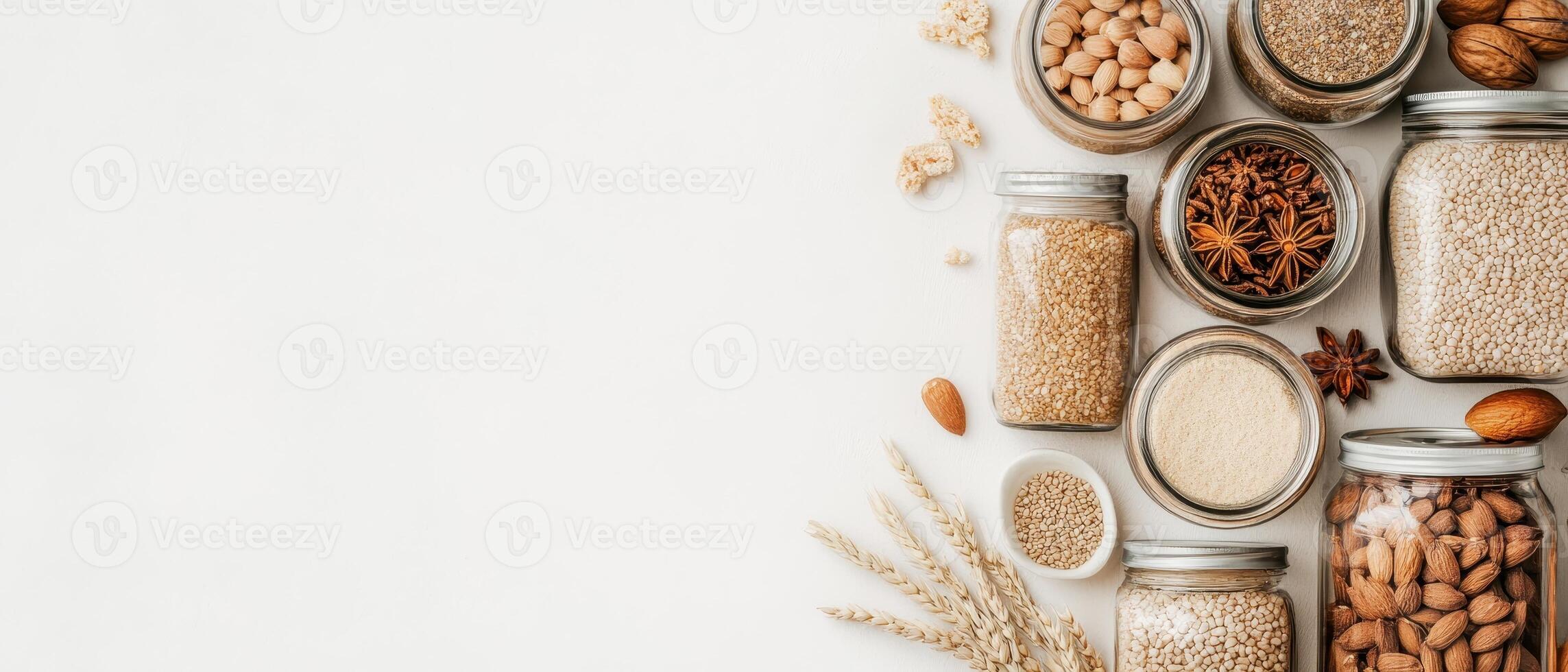 Assortment of dried foods and grains in glass jars on a plain surface. Seeds and nuts stored for eating healthy natural ingredient variety. Top view. photo