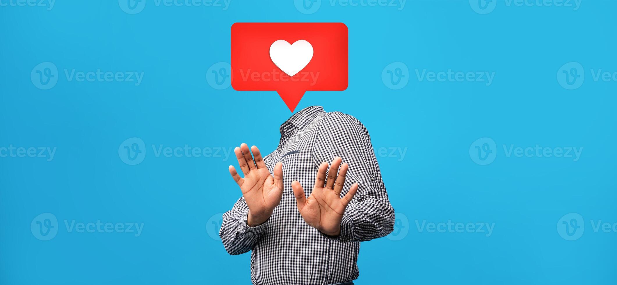 A person wearing a checkered shirt holds both hands up as if expressing hesitation. Above their head is a heart-shaped symbol, representing social media engagement. photo