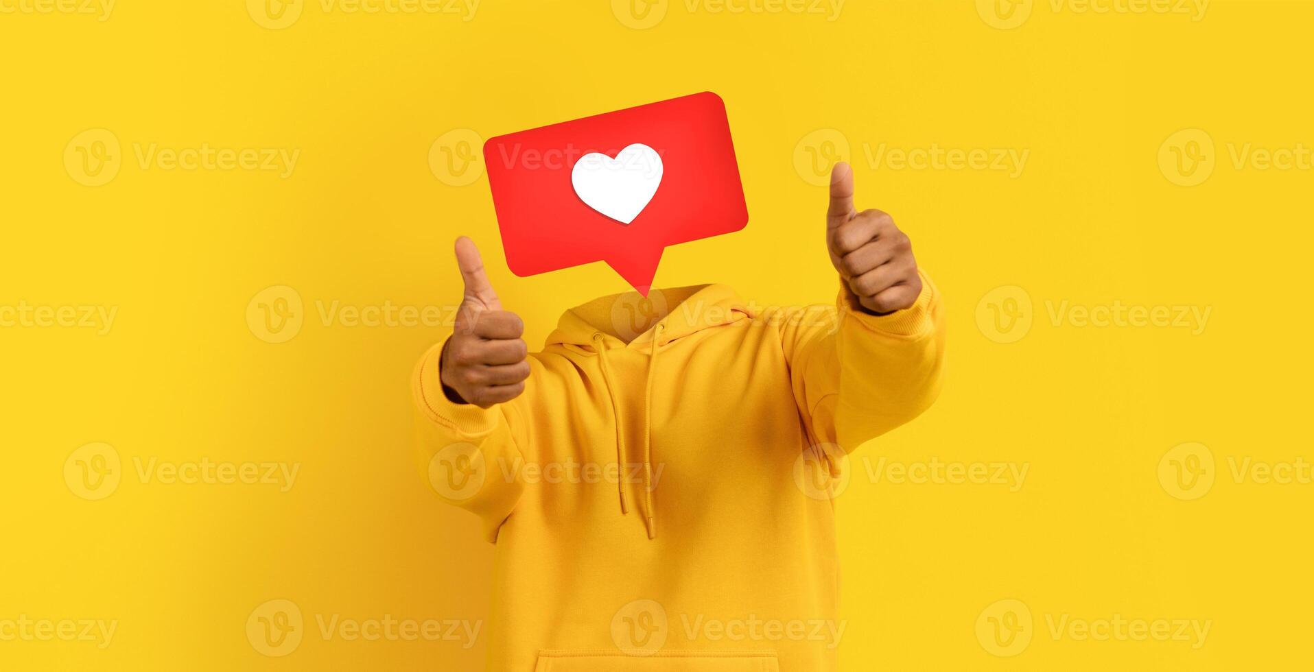Individual enthusiastically shows thumbs up with large heart icon instead of head. The vibrant yellow background adds energy, perfect for expressing positivity and likeability on social media. photo
