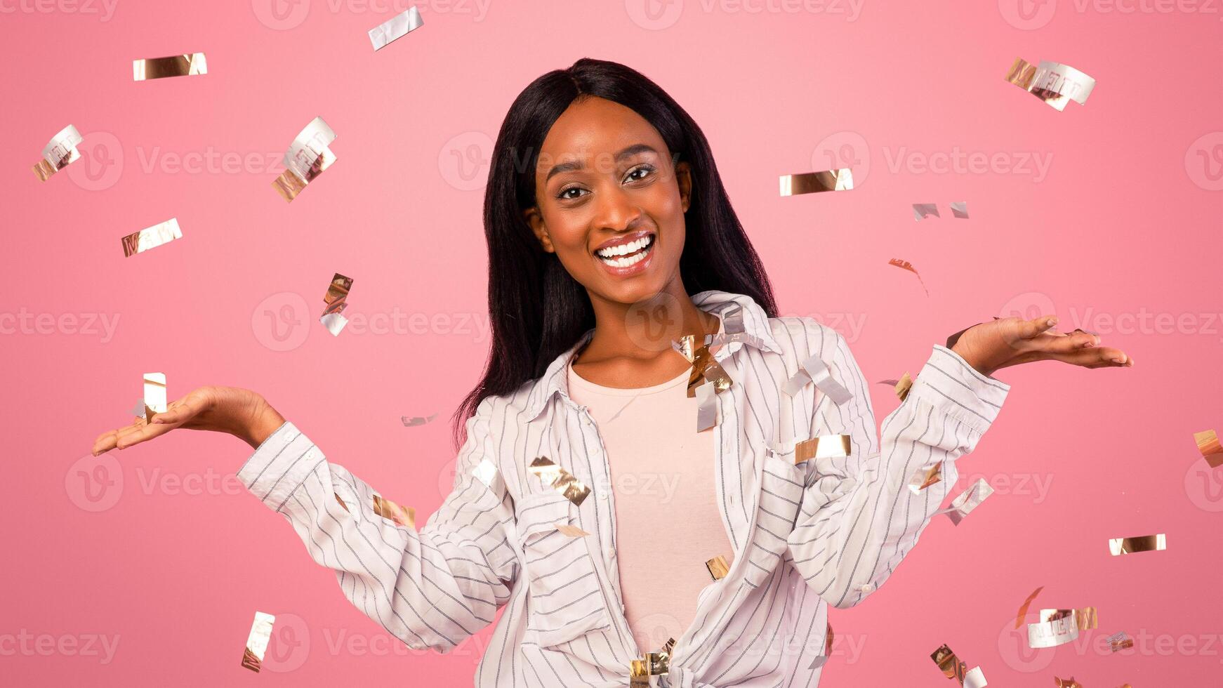 Choice options for holiday sale. Cheerful black woman comparing variants, advertising products, holding invisible objects on pink studio background with falling confetti, mockup for design photo