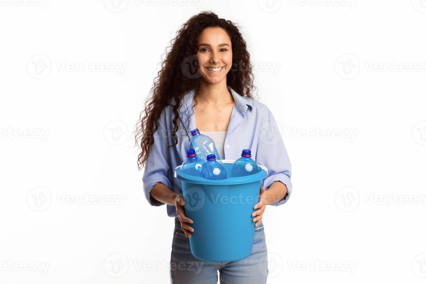 Waste Sorting. Lady Holding Garbage Bucket With Plastic Bottles And Litter Standing Over White Studio Background. Sort Your Junk, Trash Disposal And Recycling Concept photo