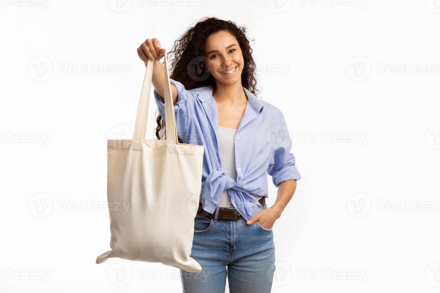 Smiling Lady Showing White Eco Bag To Camera Standing Over White Studio Background. Female Customer Posing With Eco-Friendly Textile Shopper Handbag. Stop Using Plastic, Shopping And Ecology photo