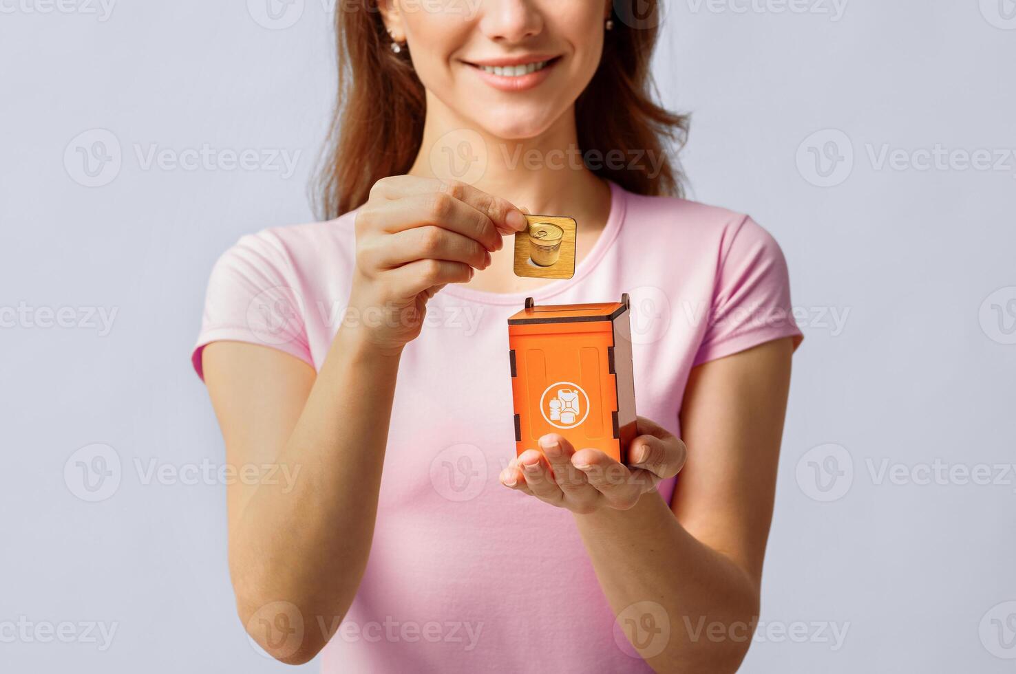 Metal Waste Recycling. Unrecognizable Lady Inserting Card With Aluminium Can Icon Into Wooden Toy Trash Container, Standing Over Light Studio Background, Conceptual Image For Garbage Sorting, Closeup photo