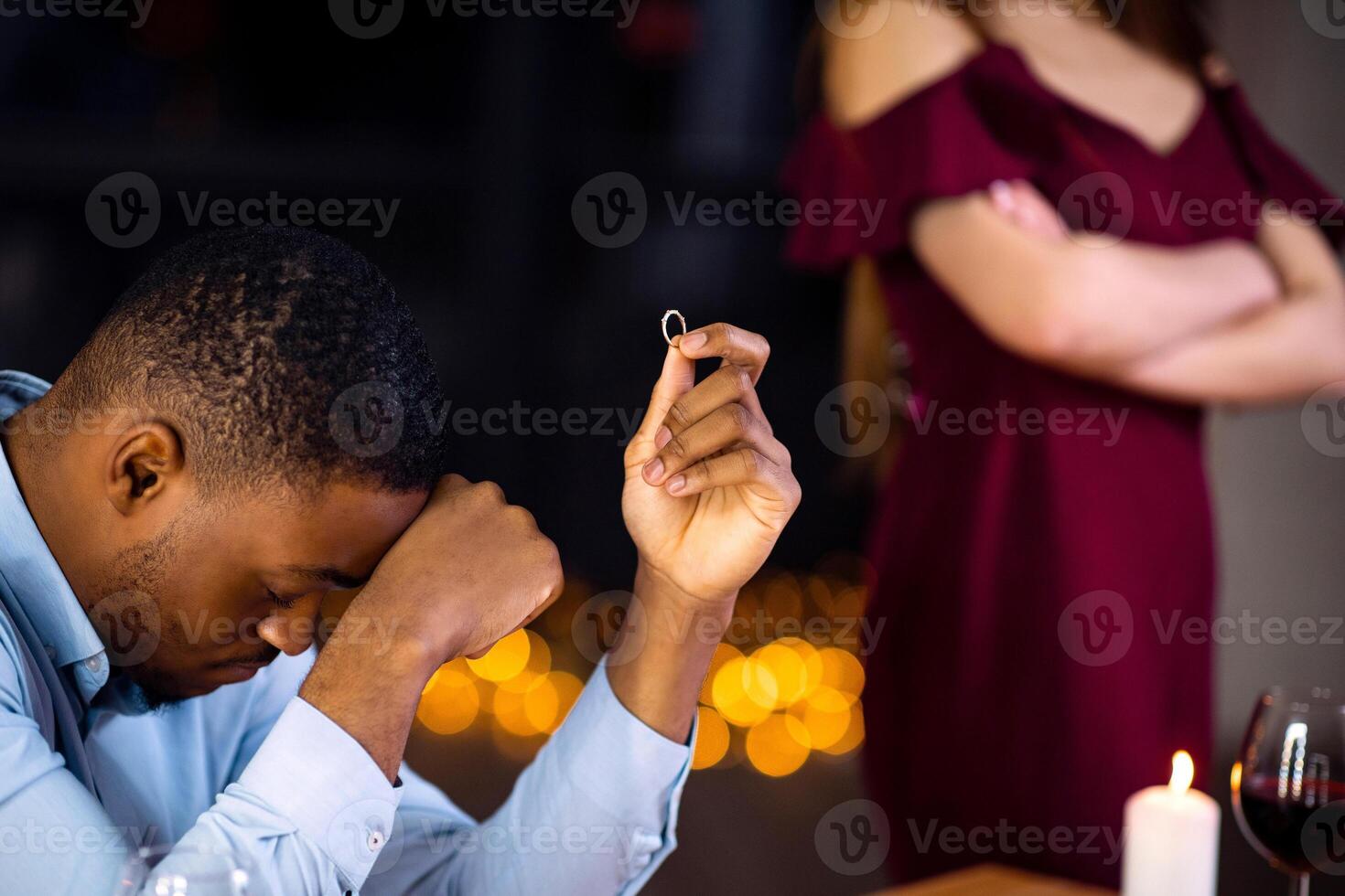 Desperate Black Man Sitting At Table With Ring In Hand After Girlfriend Refused His Proposal And Not Accepting Engagement Offer. Young African American Guy Feeling Lonely And Depressed, Cropped Image photo