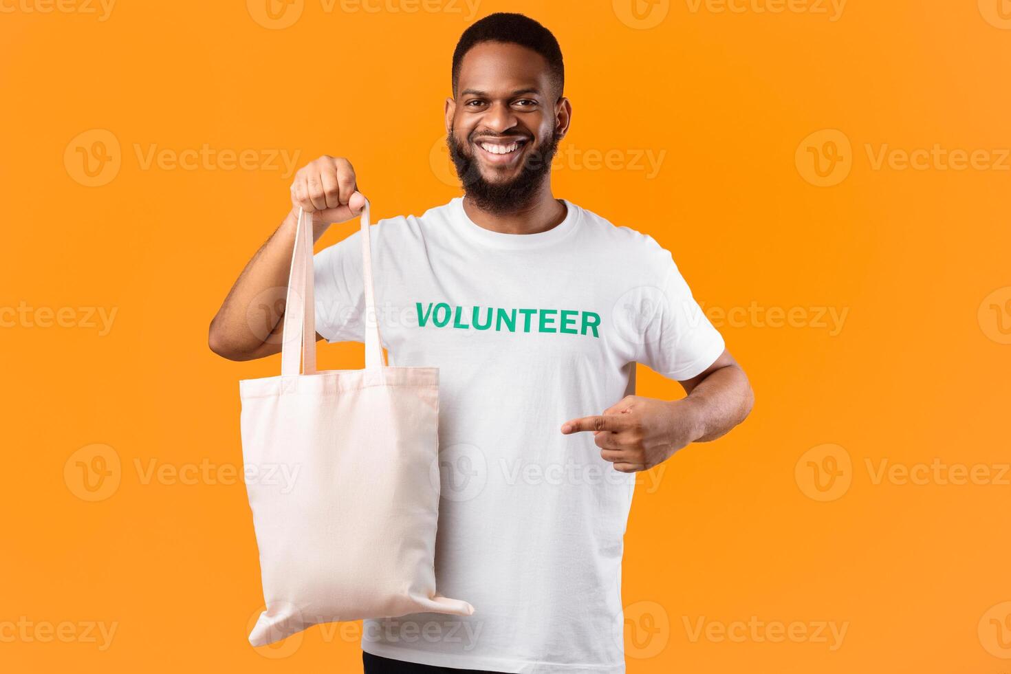 No Plastic. African Male Volunteer Pointing At White Eco Bag Standing On Yellow Studio Background. Ecology And Plastic-Free Consumerism, Eco-Friendly Lifestyle Concept photo