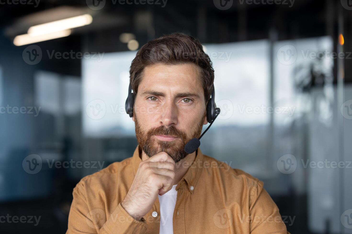 Mature businessman wearing headset focused on communication in modern office setting. Professional attitude, engagement in customer service, and expertise in business communication conveyed. photo