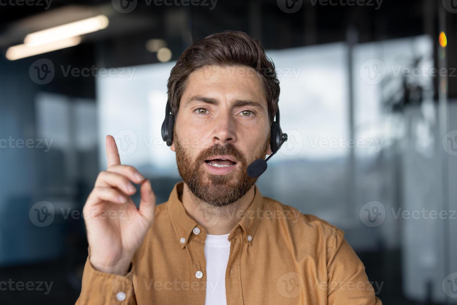 Business professional on call using headset communicates key points while gesturing to emphasize ideas. Office setting enhances focus on remote work and modern communication technology. photo