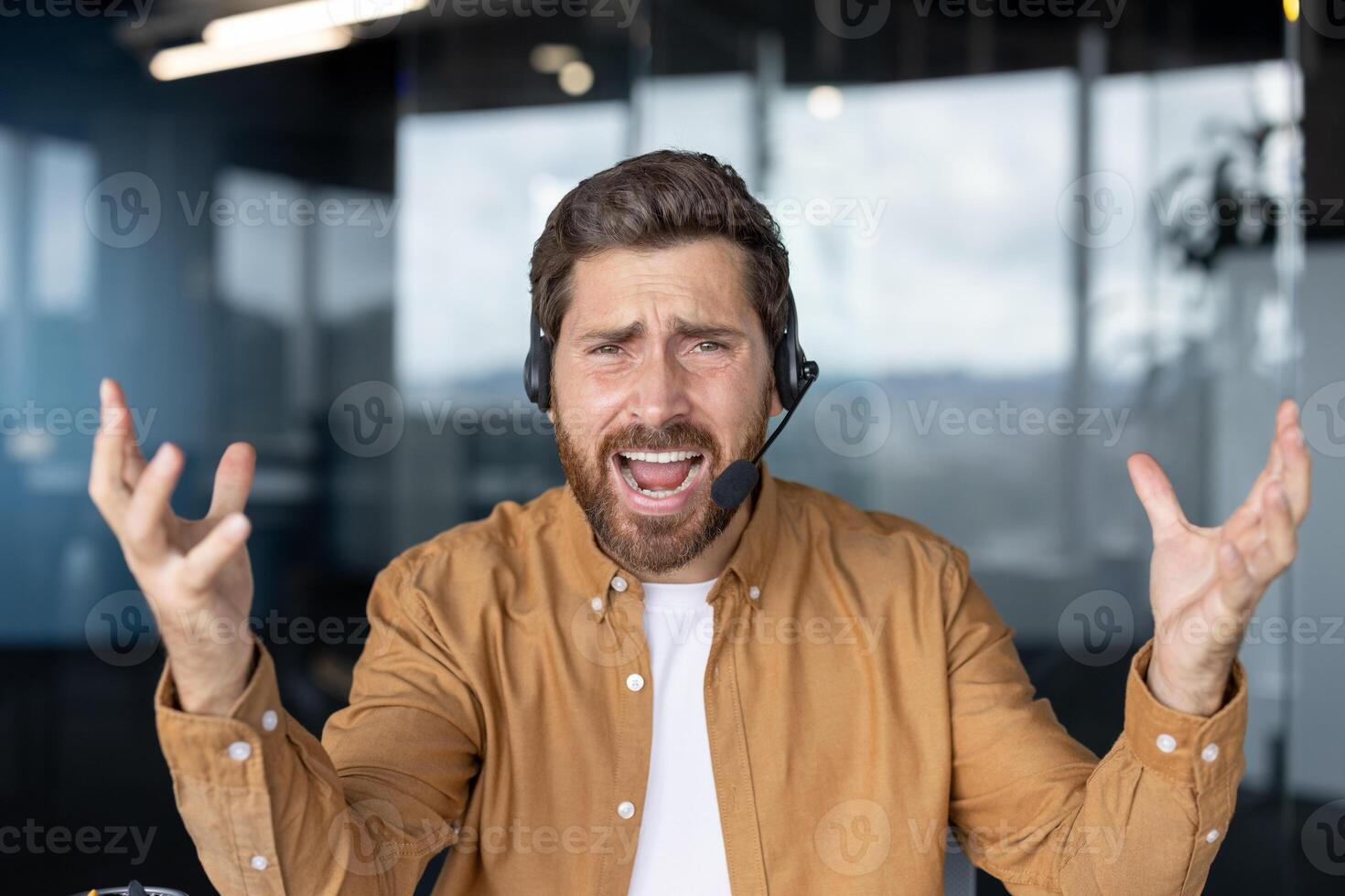 Businessman wearing headset looking frustrated handling a difficult customer support call. Professional man displaying feelings in tech office setting. Concept service communication. photo