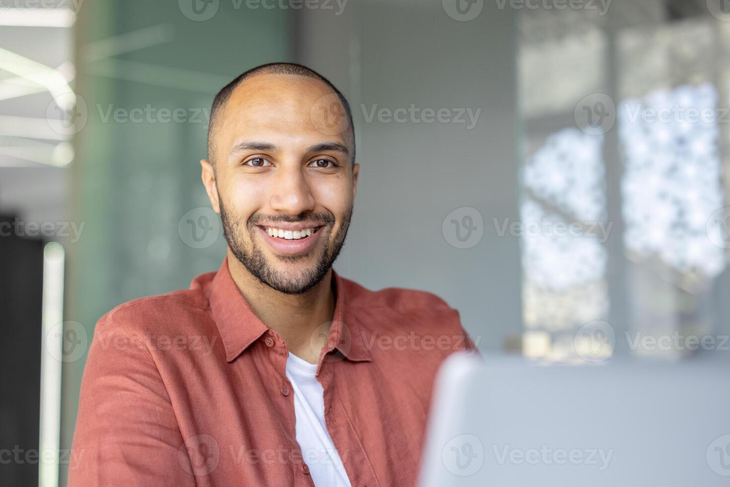 A smiling, attractive man looking towards the camera, wearing a button-down shirt. He appears happy and content. photo