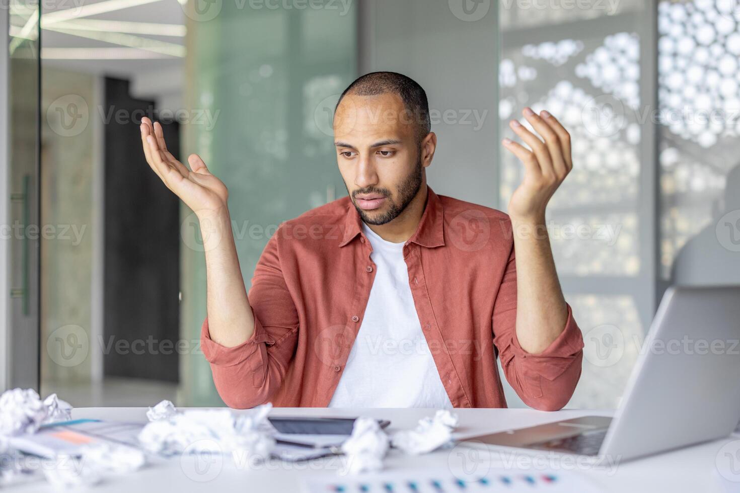 Sad frustrated financier accountant at workplace inside office. Man sitting at desk with laptop, unable to complete financial report, and fill out tax forms. photo