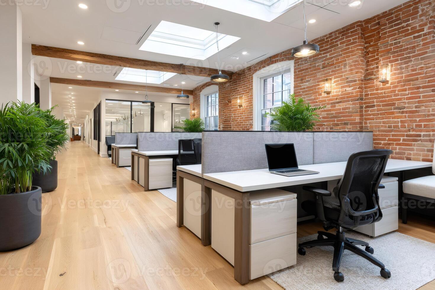Modern coworking space with exposed brick wall and skylights providing natural light photo