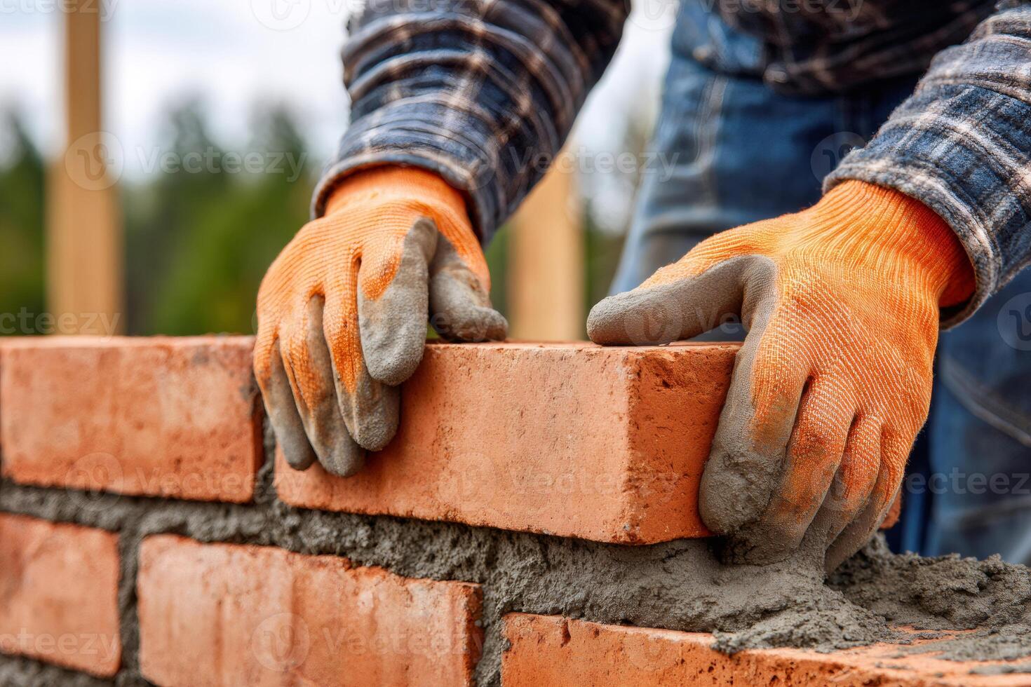Construction worker building a brick wall, placing bricks with cement mortar photo