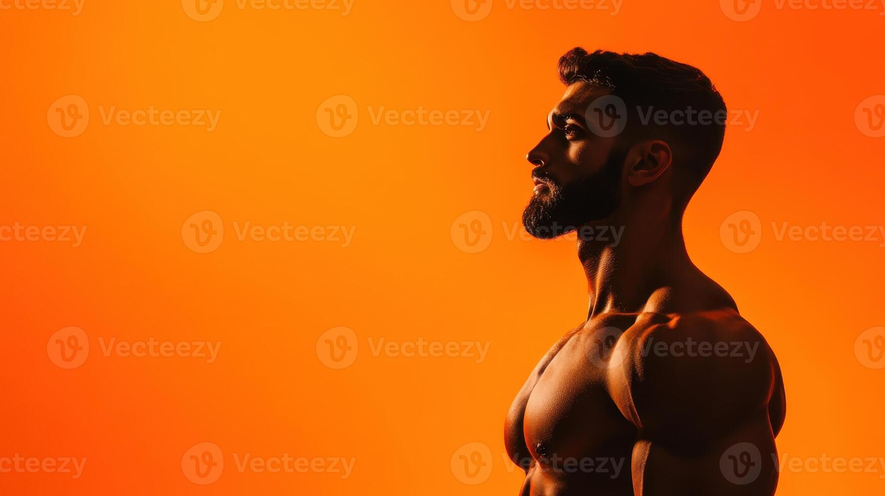 Strong man posing against a vibrant orange backdrop showcases muscular physique during a fitness photo session, emphasizing strength and determination in a gym environment
