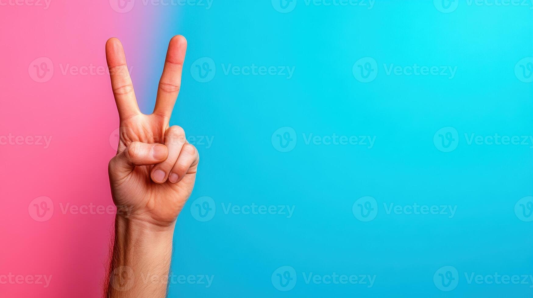 Hand gesture showing peace symbol against a bright blue and pink background during a vibrant creative event or social gathering highlighting positivity and goodwill photo