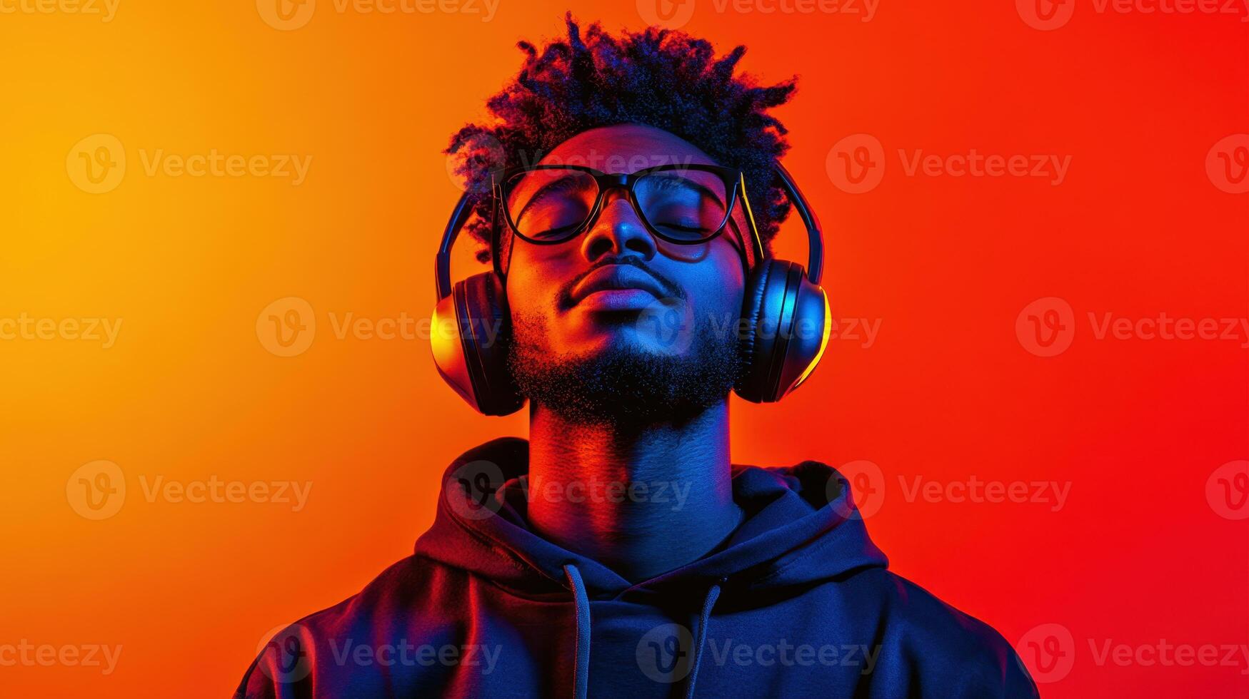 Young man enjoying music with headphones against a vibrant orange and yellow background, showcasing a moment of relaxation and connection with sound photo