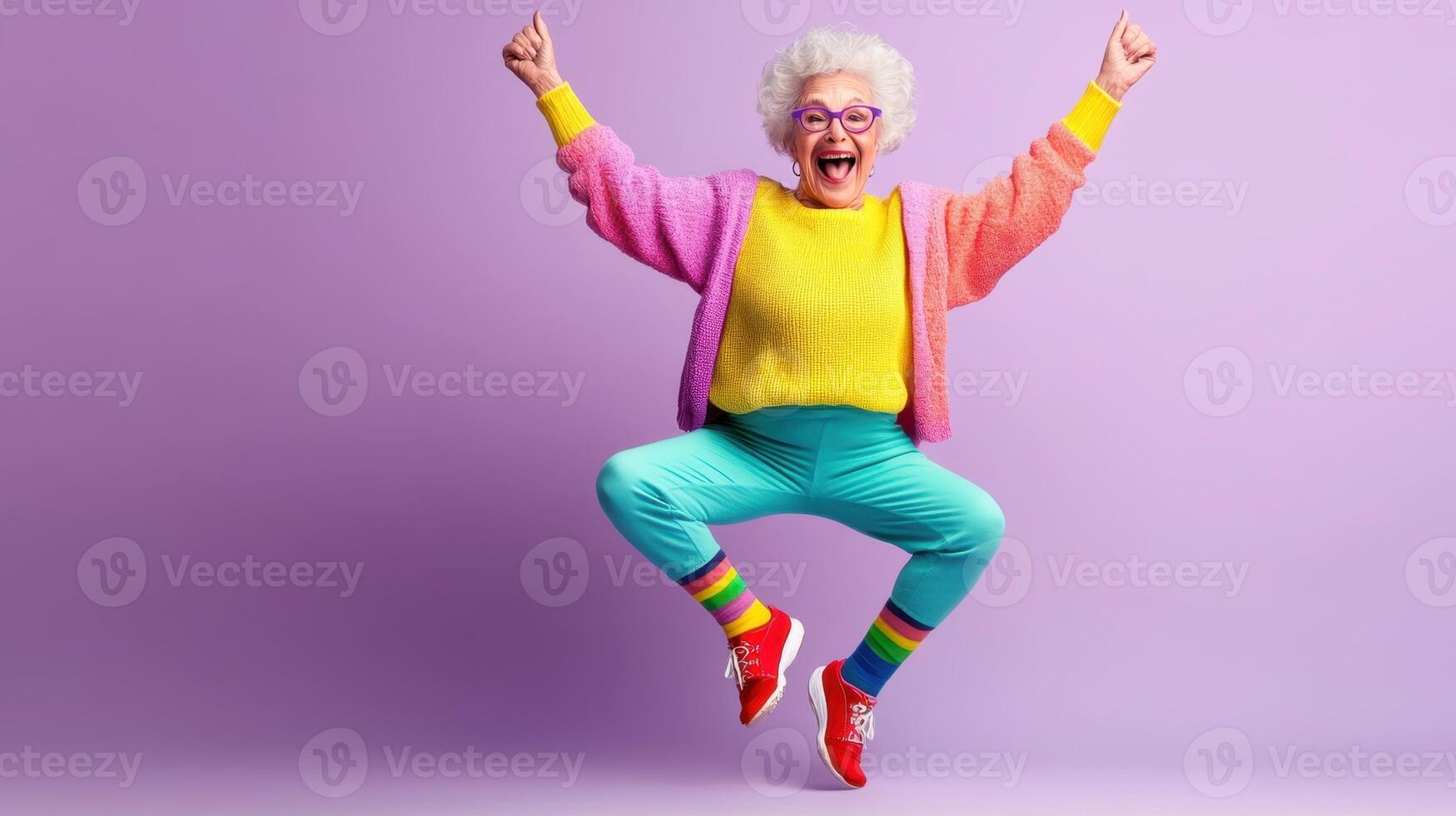 Joyful elderly woman jumping in colorful outfit celebrating positivity and happiness in a vibrant studio setting photo