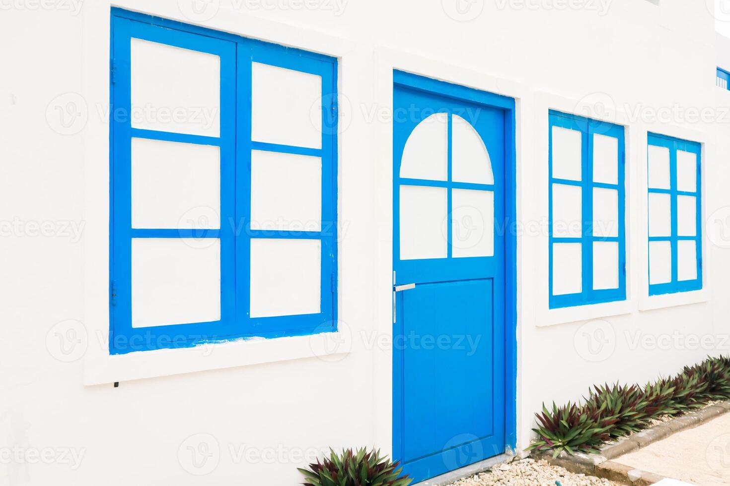 Vibrant Blue Door and Windows on a Whitewashed Building with Lush Green Plants photo