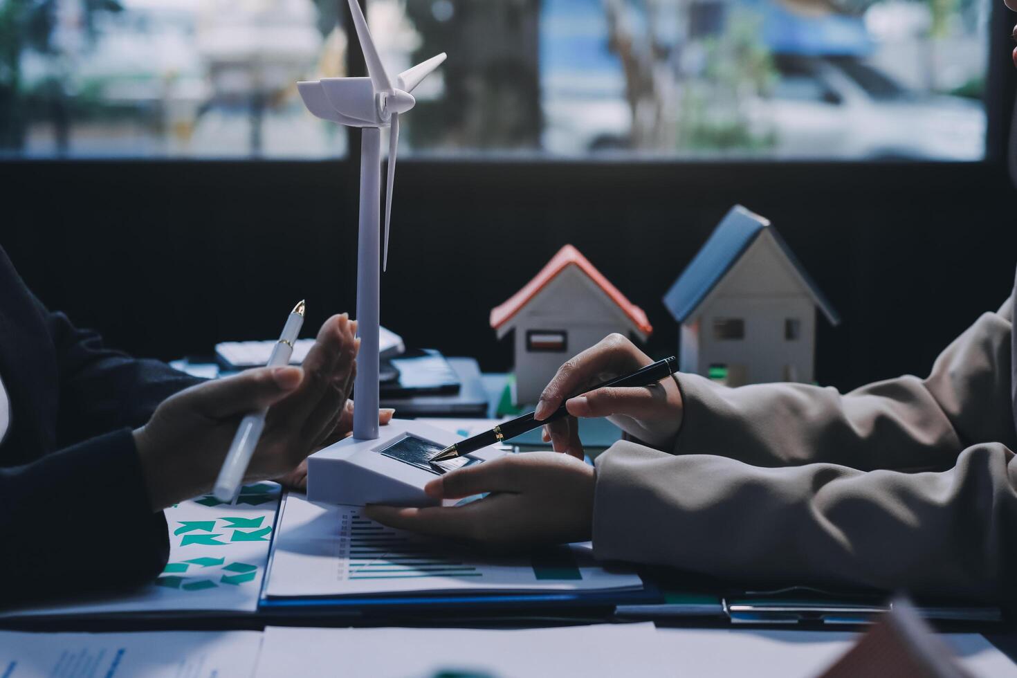 Two people working on a project together with a house model photo
