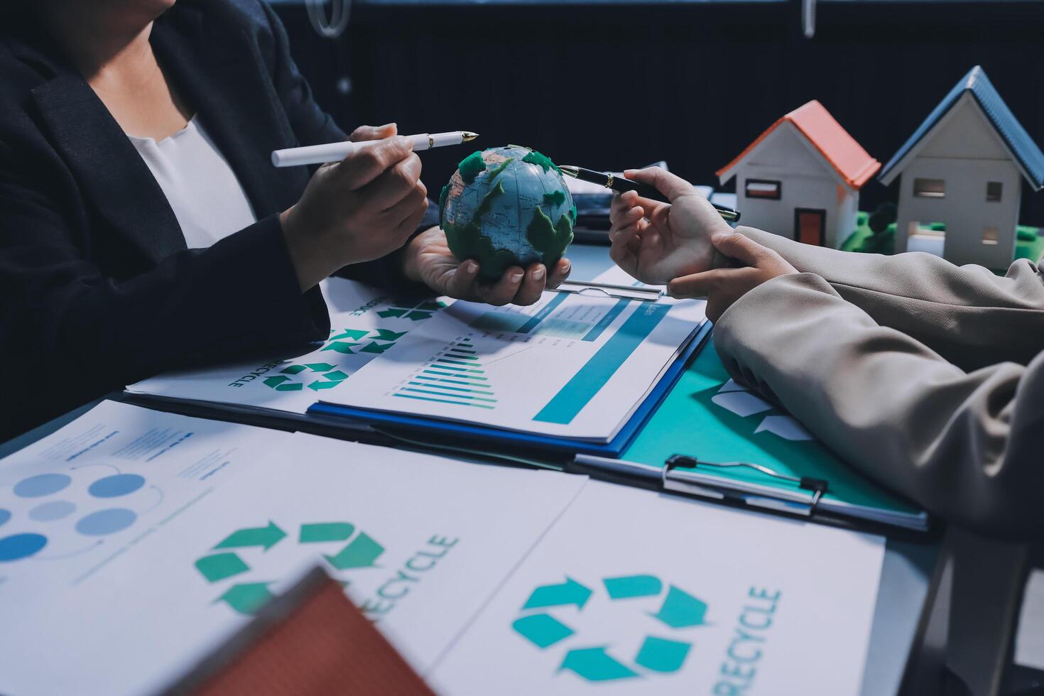 Business people working on a project with a paper model of a house and a globe photo
