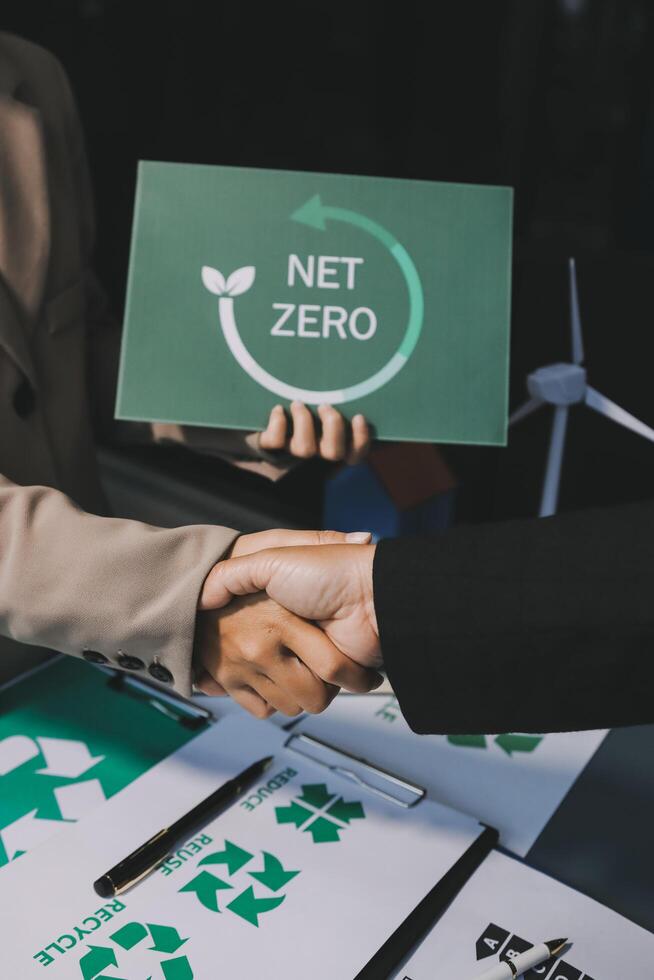 Two people shaking hands over a net zero sign photo