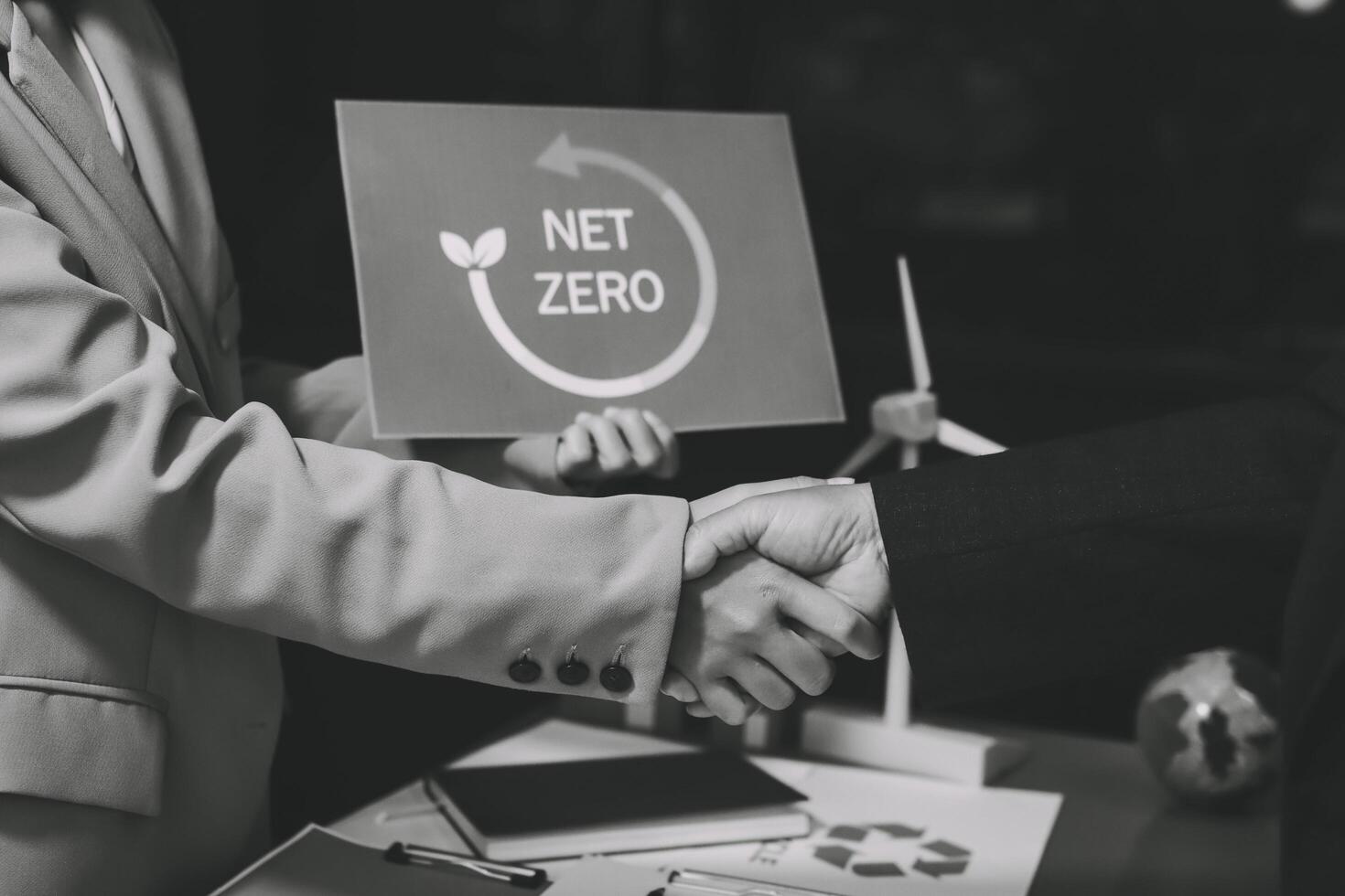 Two people shaking hands with a net zero sign photo